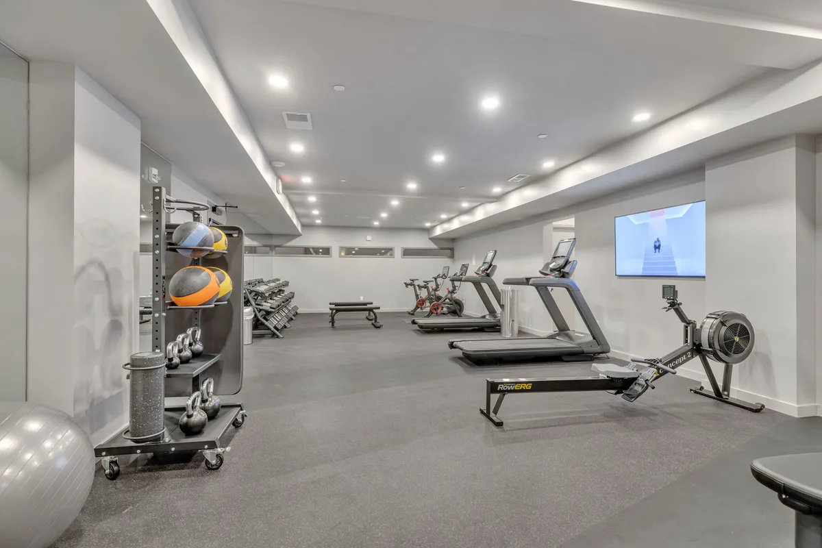A state-of-the-art fitness center with treadmills, exercise bikes, rowing machines, free weights, and medicine balls. The mood is energetic, encouraging guests to recharge after a day of meetings or events.